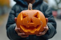 A kid holding halloween pumpkin food anthropomorphic jack-o'-lantern.