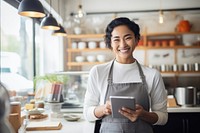 Woman at a cafe with a tablet at cashier smiling adult entrepreneur.