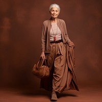 A senior woman walking in studio overcoat handbag fashion.