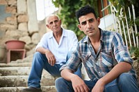 Middle eastern son and senior father sitting architecture portrait.