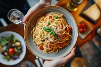 Hands holding pasta dish restaurant spaghetti plate.