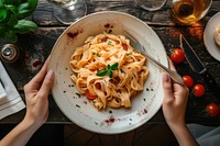 Hands holding pasta dish restaurant plate food.