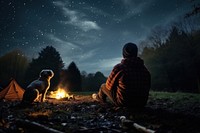 Young alone people and their pets camping in autumn night fire outdoors.