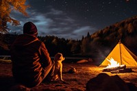 Young alone people and their pets camping in autumn night outdoors bonfire.