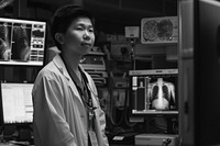 An asian radiology technician standing in front a workstation hospital adult architecture.