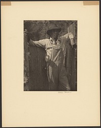 Man in Overalls Leaning Against Old Fence by Doris Ulmann