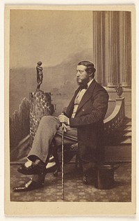 Unidentified bearded man seated, holding a walking stick by F W Baker