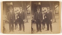 White beared man wearing a derby standing on a platform with a train conductor and three boys