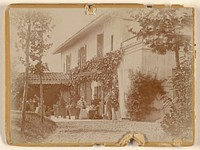 Group of people with two dogs at front of house, some seated