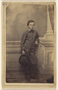 Unidentified well-dressed young boy standing, holding a derby by S B Howard