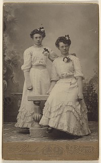 Two unidentified women wearing identical white dresses, both with flowers in hair and on dresses by Mathilda Ranch