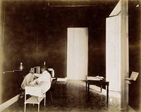 A tuberculosis patient undergoing an examination, Cuba: a doctor is shown examining the face of a patient, seated at a dispensary examination table. Photograph, 1902.