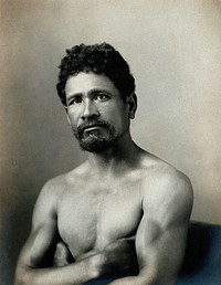 A barechested, bearded Samoan man, with his arms crossed.