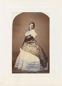 A man in drag poses wearing an elaborate dress. Coloured photograph, 189-.
