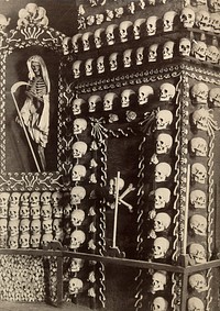 Skulls and skeletons of friars arranged columns around the walls of a chapel. Photograph.
