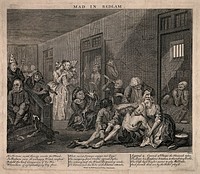 An insane man (Tom Rakewell) sits on the floor manically grasping at his head, his lover (Sarah Young) cries at the spectacle while two attendants attach chains to his legs; they are surrounded by other lunatics at Bethlem hospital, London. Engraving by W. Hogarth, 1735.