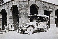 Two men in a car outside the Wellcome pharmaceutical depot in the Middle East. Photograph.