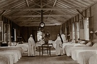 Leper asylum, Port of Spain, Trinidad: two nuns (working as nurses) in a hospital ward with empty beds. Photograph, 1890/1910.
