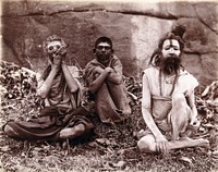 Two men and a boy sitting cross-legged on the ground surrounded by leaves; their faces are painted white and one of them appears to be smoking a pipe: Bombay at the time of the plague. Photograph, 1896/1897.