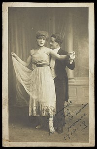 Two actors, one in drag, dancing together on stage. Photographic postcard, 1918.