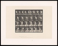 Two men in posing pouches stand, facing one another, fists raised: one grasps the other round the chest with his left arm, bends, lifting and swinging him over his back, legs in the air. Collotype after Eadweard Muybridge, 1887.
