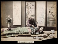 A Japanese woman being massaged by a blind Japanese masseur. Coloured photograph.