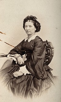 A woman sitting down, her right eyelid is heavier than her left. Photograph by L. Haase after H.W. Berend, 1865.