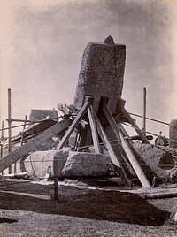 Stonehenge, England: the straightening of a leaning stone which is attached to a wooden frame and supported by beams: north east view. Photograph, 1901.