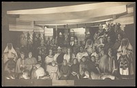 Amateur actors, some in drag, pose on a crowded stage. Photographic postcard, 191-.