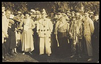 People at Rickmansworth, Herts., some in drag, gather outside at a swimmming gala. Photographic postcard, 1908.
