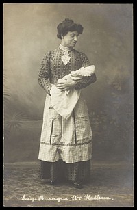 A man in drag holding a baby. Photographic postcard by Photo Jos. Dumont.
