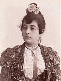 A female bullfighter, with flowers in her hair, wearing a matador's jacket. Photograph by Castillo, ca. 1900.