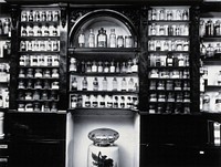 Savory & Moore Ltd, London: the interior of the pharmacy; wooden shelves with labelled bottles and jars holding drugs. Photograph.