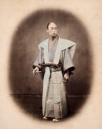 Japan: a samurai (a 'yakonin') in ceremonial dress. Coloured photograph by Felice Beato, ca. 1868.