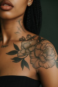 Photo of a black female upper arm with flower tattoo skin individuality midsection.