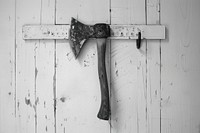 Axe hanging from hook from the wall tool monochrome weathered.