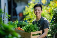 Young Chinese man carrying a vegetable box garden gardening outdoors.