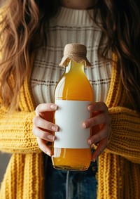 Woman holding a bottle of apple juice drink refreshment midsection.