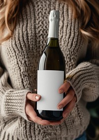Woman holding a bottle of sparkling sweater drink wine.