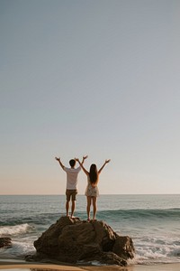 Couple standing on a rock at the beach outdoors vacation adult.