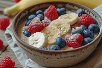 Bowl of oat porridge blueberry raspberry banana.