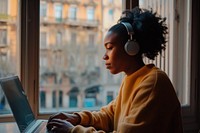Black woman typing on laptop headphones computer headset.