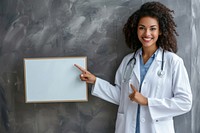 A smiling female doctor is pointing at mini white board stethoscope blackboard physician.