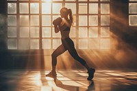 A woman kickboxing in a bright gym to get a workout running adult determination.