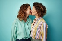 A lesbian couple wearing colorful shirts kissing adult blue.