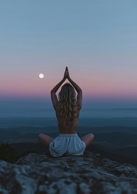 A woman silhouette sitting put the hand together above the head or doing yoga on the mountain in front of the moon astronomy outdoors nature.