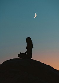 A woman silhouette sitting put the hand together or doing yoga on the mountain in front of the moon astronomy outdoors nature.