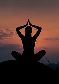 A woman silhouette sitting put the hand together above the head or doing yoga on the mountain in front of the moon backlighting sky spirituality.