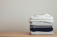 A stack of sweatshirts on a table white coathanger textile.