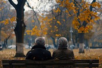 Happy elderly couple sitting outdoors autumn.